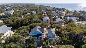 Et kystnære boligområde med huse omgivet af tætte træer og havudsigt.