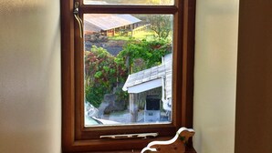 A corner of a room with a wooden floor, a window with a view of a house and trees, and a small wooden toy horse on the floor. - Little Dunley - Virginia Cottage (Bovey Tracey)