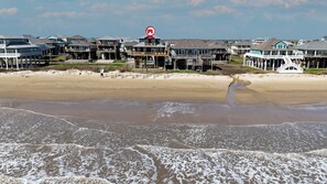 Una propiedad frente a la playa con varias casas, algunas con balcones, y una playa arenosa al frente.