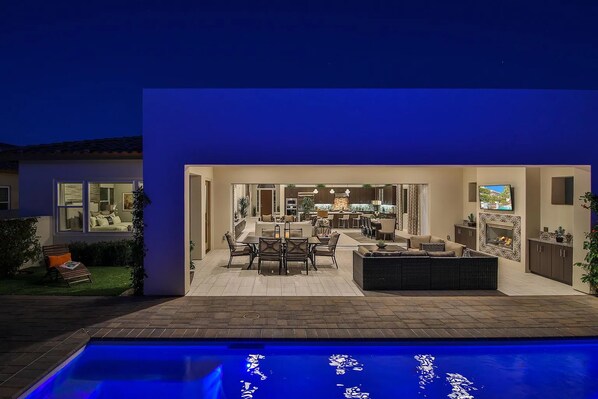 A modern house with a swimming pool, a dining area, and a kitchen.