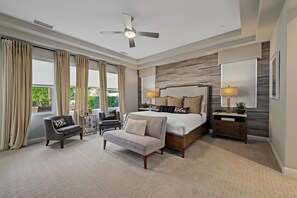 A bedroom with a bed, a sofa, a chair, a nightstand, and a ceiling fan.
