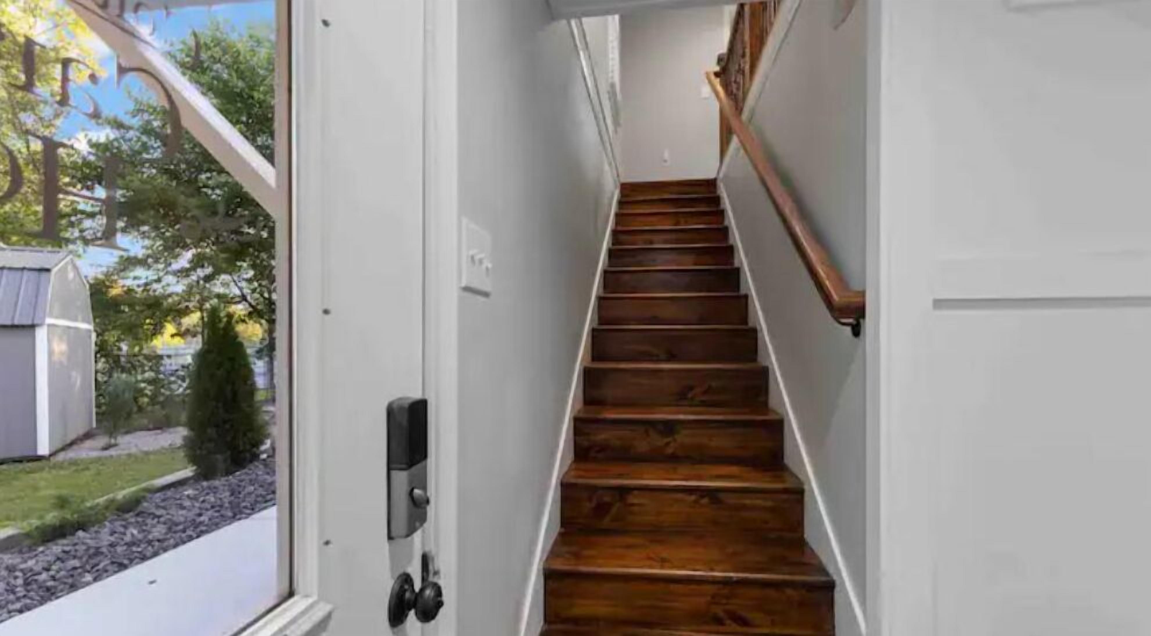 A narrow hallway with wooden stairs leading to a door.