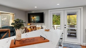 A modern kitchen with a marble countertop, a coffee table, a television, and a sliding glass door leading to an outdoor area. - Your home away from home in downtown, historic Farmington! (Farmington)