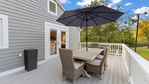A deck with a table and chairs, a trash can, and a large umbrella. - Your home away from home in downtown, historic Farmington! (Farmington)