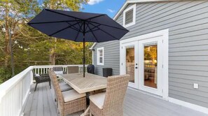 A deck with a table and chairs, a black umbrella, and a house with a white door. - Your home away from home in downtown, historic Farmington! (Farmington)