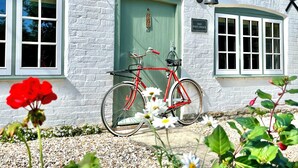 Un edifici blanc amb una porta verda, una bicicleta vermella i un rètol que diu "Old Post Office".