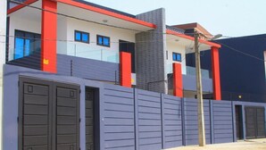 Un bâtiment moderne à la façade rouge et blanche, aux murs extérieurs gris et à la porte bleue.