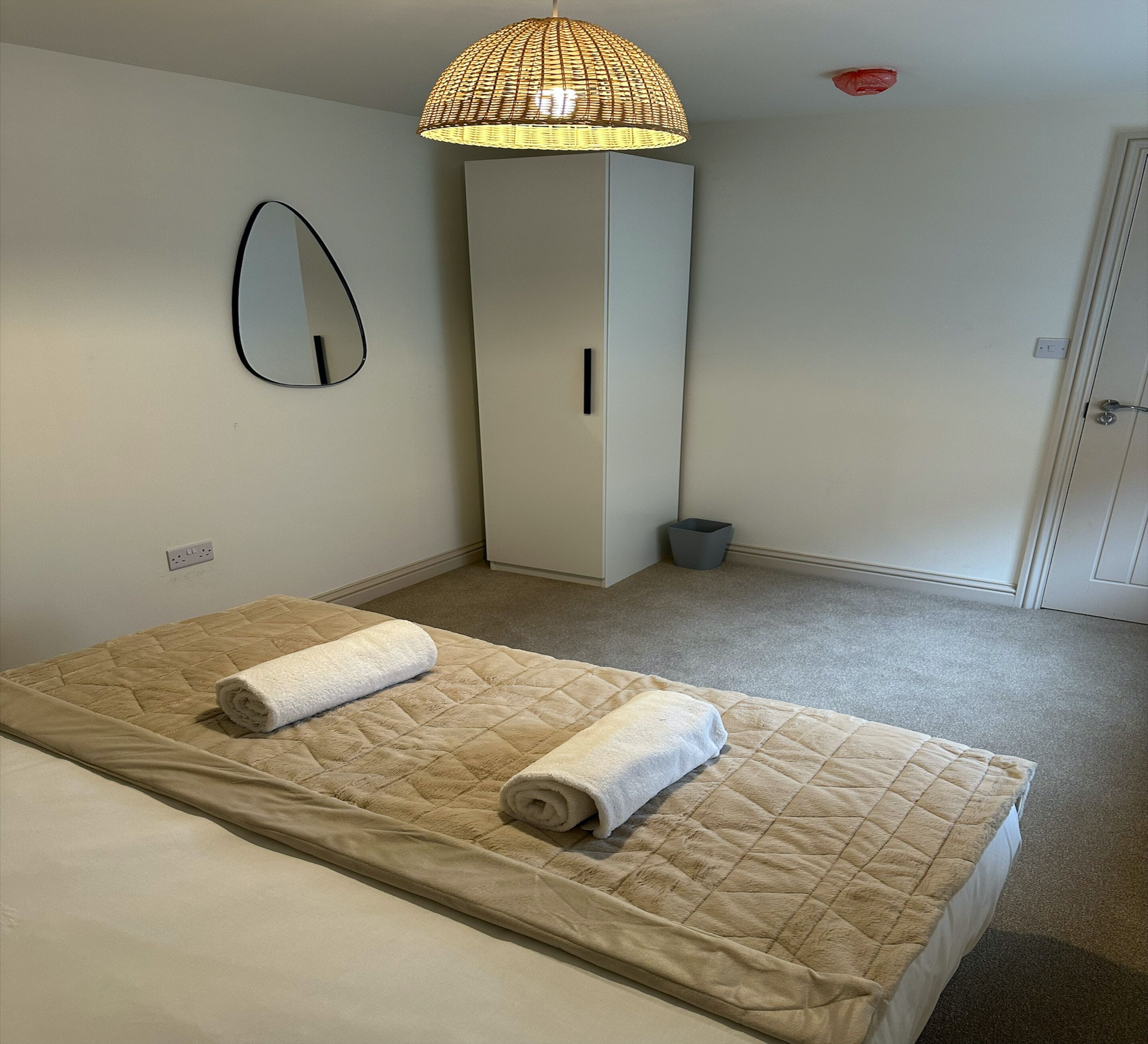 A hotel room with a bed, a bedside lamp, a wardrobe, and a mirror.