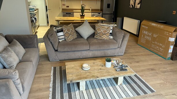 Un salon moderne avec un canapé gris, une table basse en bois et un tapis à rayures.
