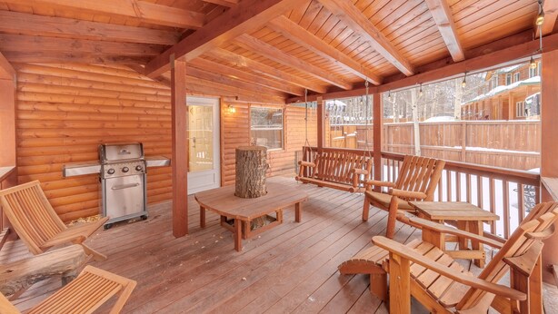 Un patio in legno con una griglia, sedie e un tavolo.