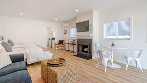 Ein modernes Wohnzimmer mit Kamin, Essbereich und einer Küche im Hintergrund.