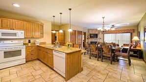 Una cocina amplia con armarios de madera, una isla central y una zona de comedor con chimenea.
