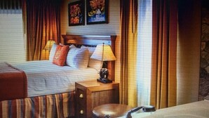 Una habitación de hotel con cama, mesita de noche con lámpara, baño con bañera y cortinas.