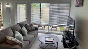 A living room with a grey sofa, a round coffee table, and a piano. - Marvel GulfCondo - One Bedroom Hotel, Sleeps 4 (Gulfport)