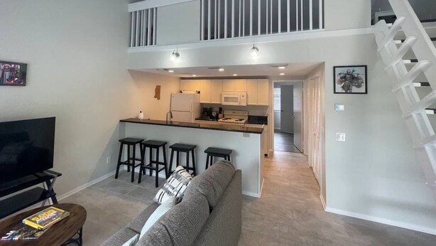 A modern apartment with a living room, kitchen, and a staircase leading to an upper level. - Marvel GulfCondo - One Bedroom Hotel, Sleeps 4 (Gulfport)