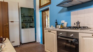 A compact kitchen with a gas stove, oven, and a glass-fronted cabinet.