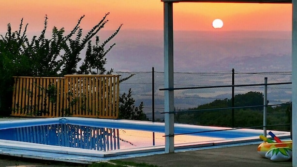 A swimming pool with a view of the sunset and distant mountains.