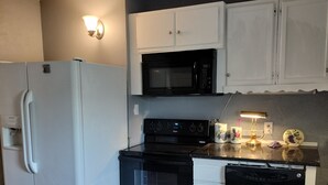 A compact kitchen with a refrigerator, microwave, stove, and dishwasher. - Experience football fun! 4BR/2Bath Independence retreat near Arrowhead (Sugar Creek)