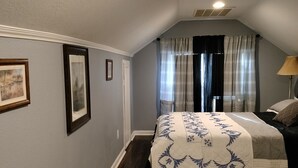 A bedroom with a bed, a window with curtains, a ceiling fan, and a wall-mounted light fixture. - Experience football fun! 4BR/2Bath Independence retreat near Arrowhead (Sugar Creek)