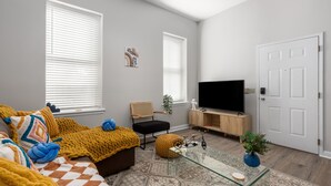 Un salon avec un canapé, une table basse, un téléviseur et une porte.