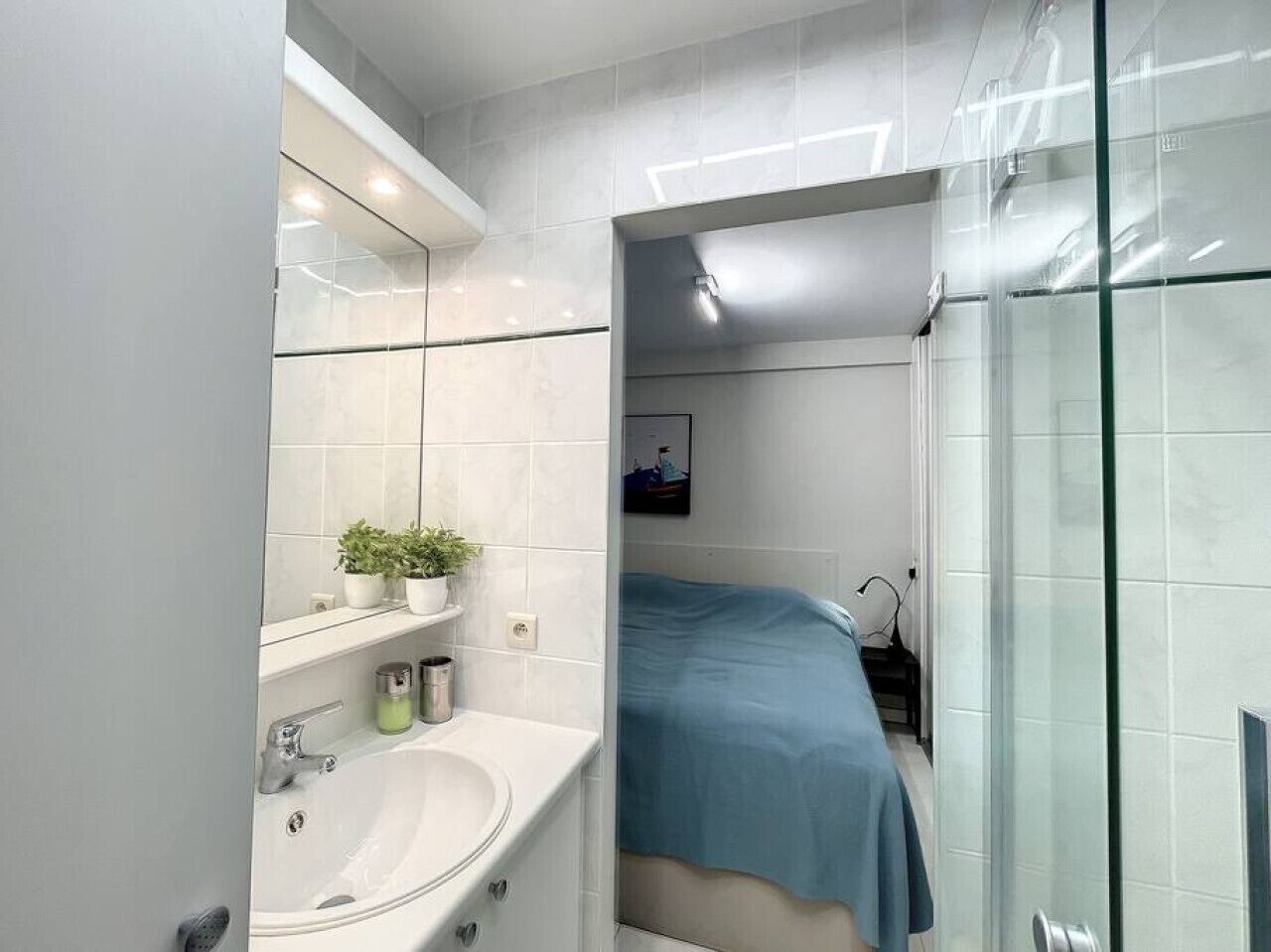 Een moderne badkamer met een witte wastafel, spiegel en een douchecabine van glas.