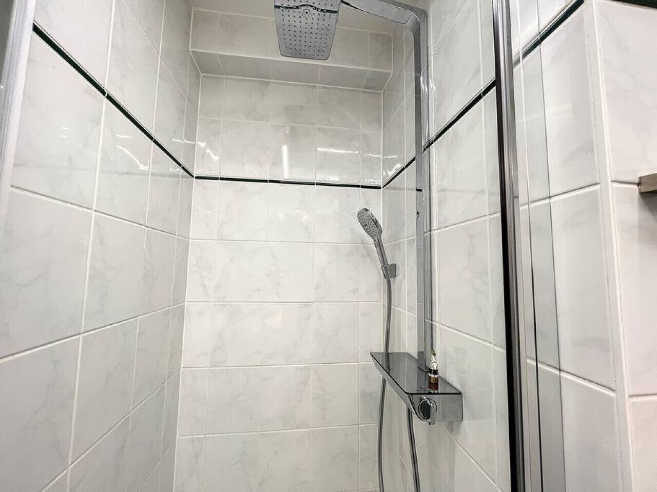 Een moderne douche met een handdouche en een douchecabine van glas.