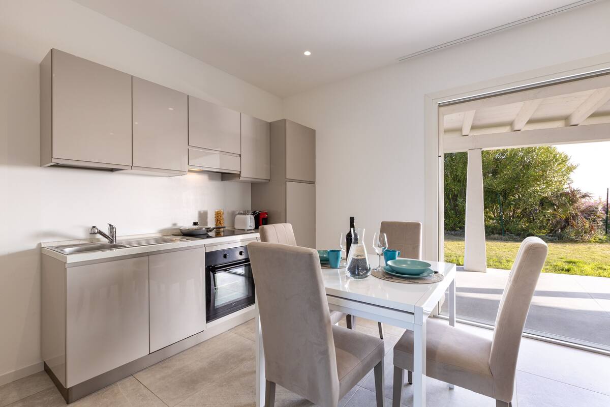 A modern kitchen with a dining area, a built-in oven, and a view of the outdoors.