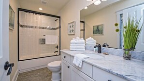 A bathroom with a shower, toilet, vanity, and a large mirror. - BeachFront 9Bed EasyBreezy East (Gulf Shores)