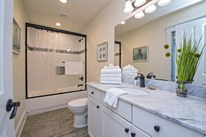 A bathroom with a shower, toilet, vanity, and a large mirror. - BeachFront 9Bed EasyBreezy East (Gulf Shores)