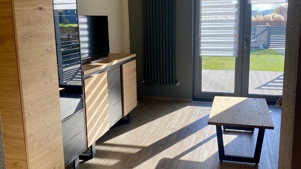 A modern kitchen with a built-in oven, a wooden cabinet, and a small table.