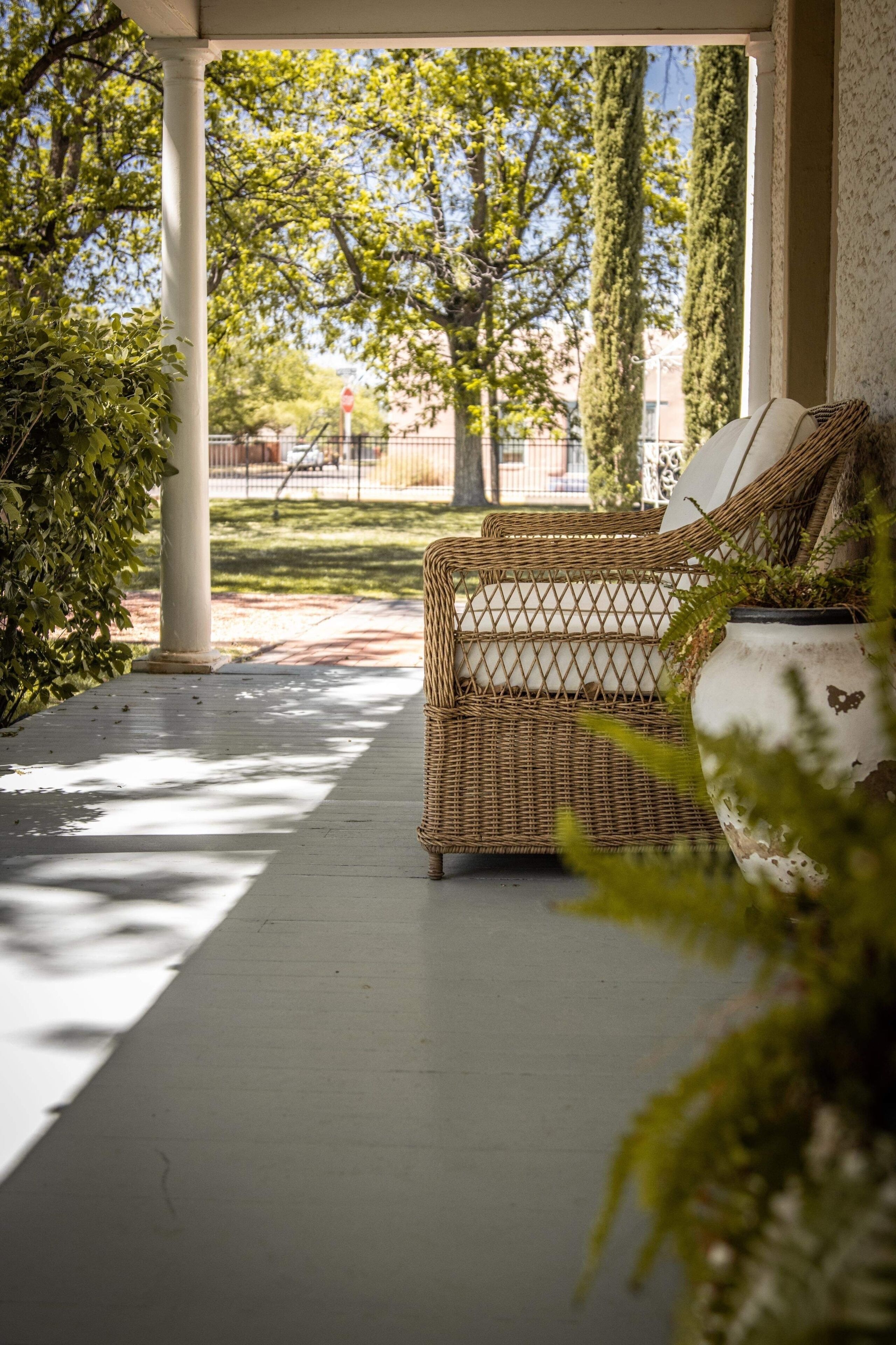 A covered porch with a wicker chair and a potted plant.