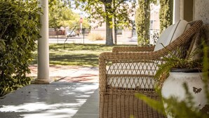 A covered porch with a wicker chair and a potted plant.