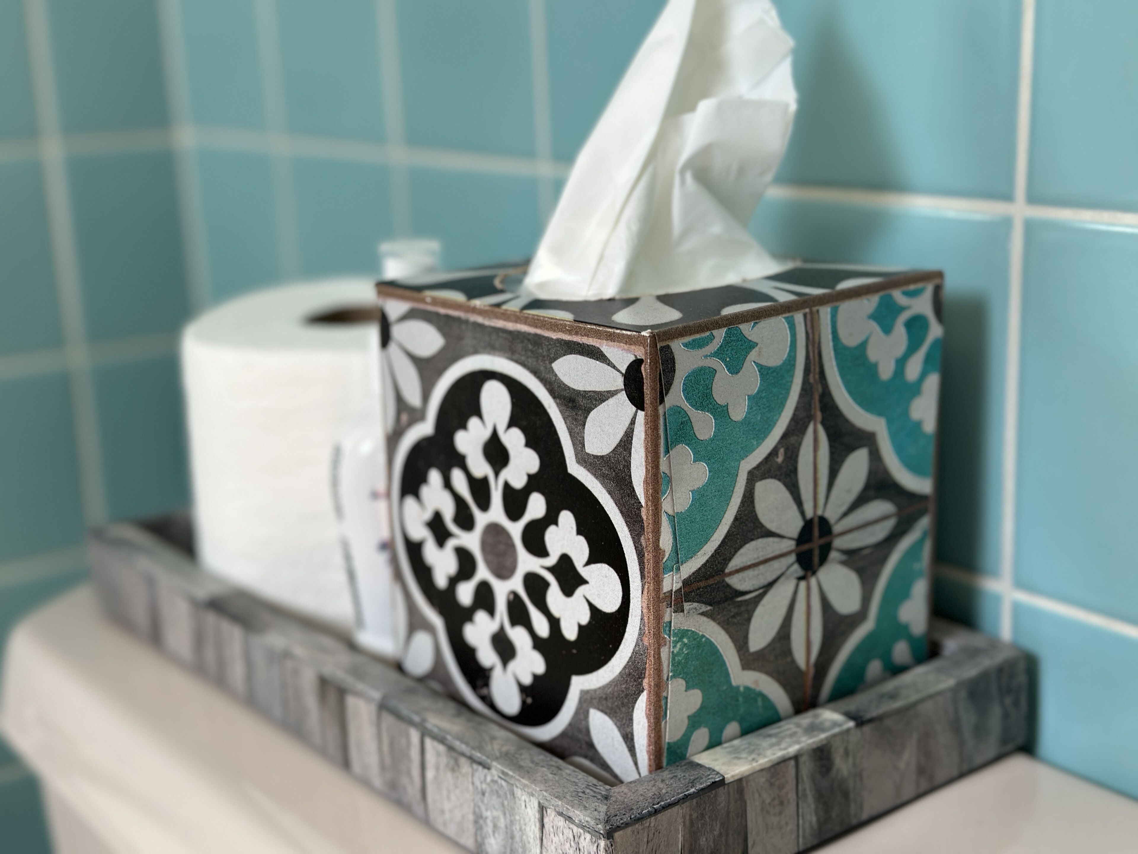 Une boîte de mouchoirs à motifs floraux, posée sur une étagère dans la salle de bain.