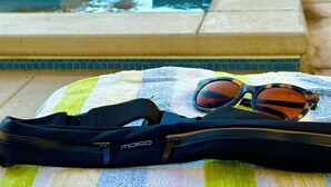 A pool area with a towel, sunglasses, and a bag on the floor.