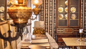 A well-lit room with a marble countertop, a cabinet with glass doors, and patterned wallpaper.