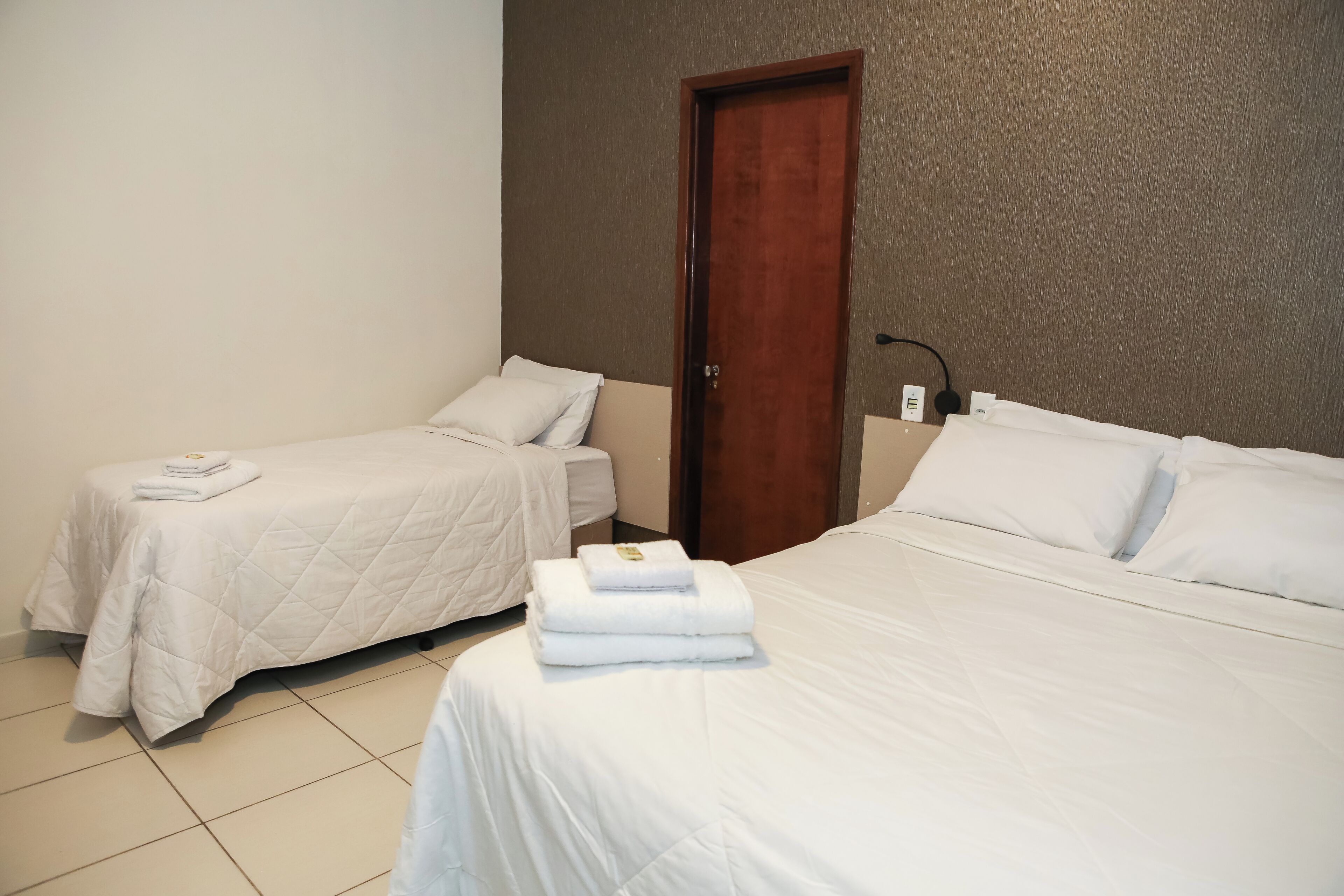 Une chambre d’hôtel avec deux lits, une porte en bois et un mur blanc.