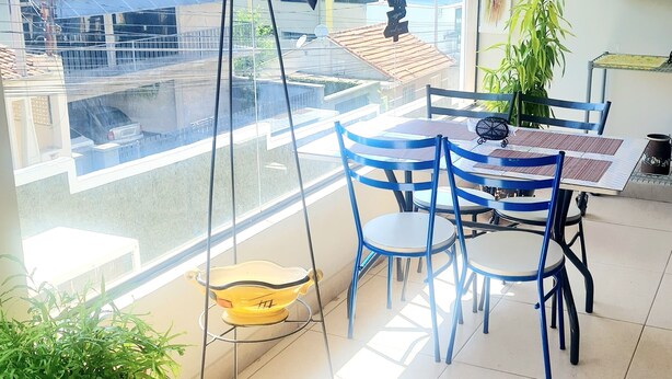 A balcony with a dining area, potted plants, and a view of the cityscape. - Acqua Flats Residence  (Jaguariuna)