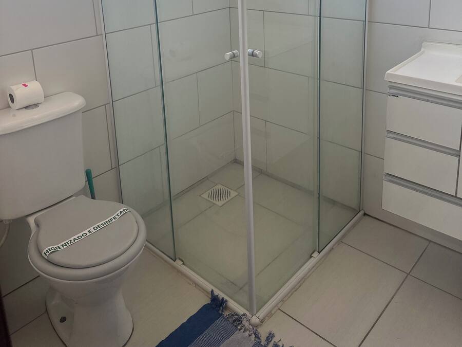 Un baño con ducha de vidrio, inodoro y lavamanos.