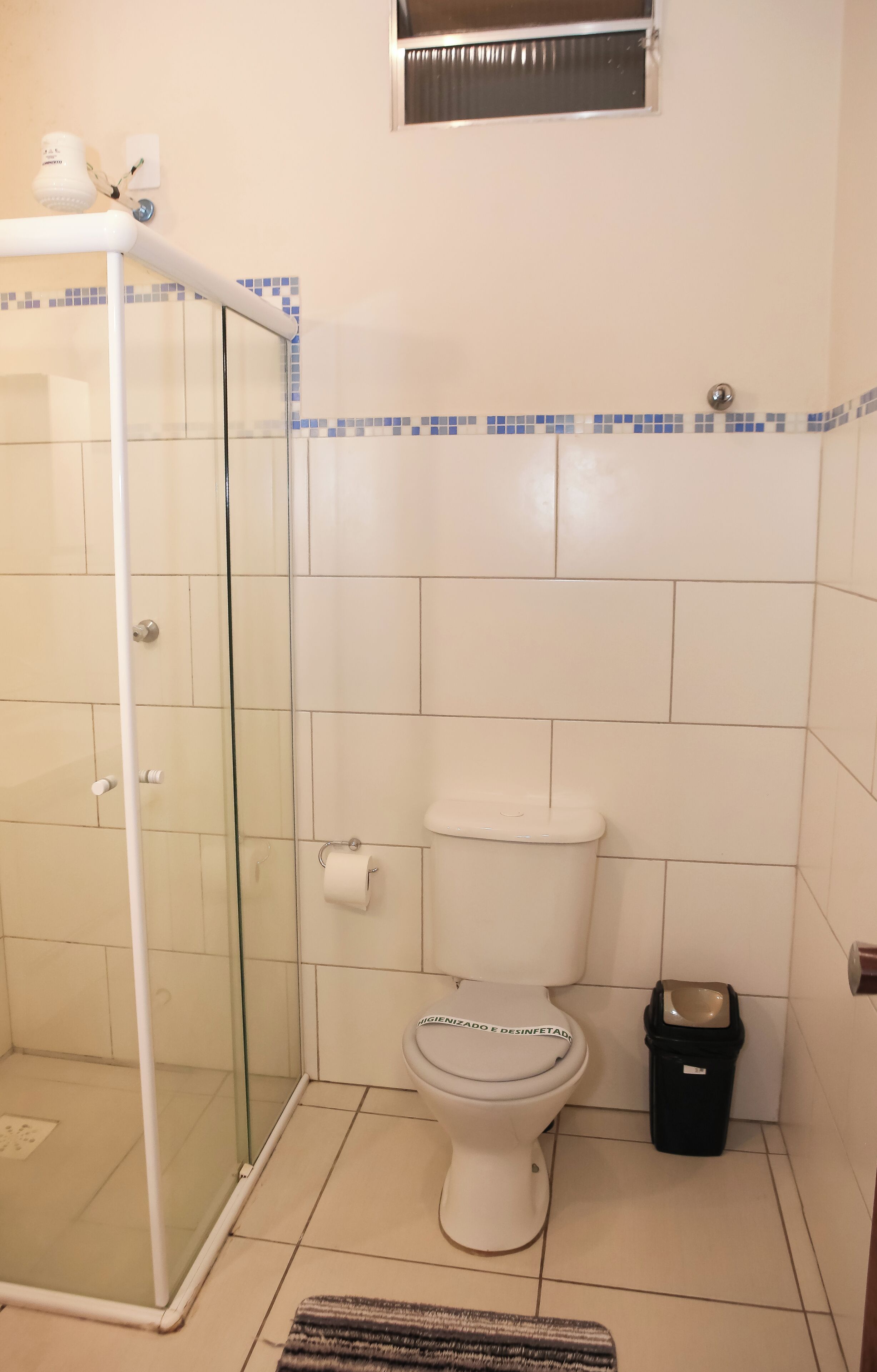 Ett badrum med en dusch som är avskärmad med glasväggar, en toalett och en papperskorg.