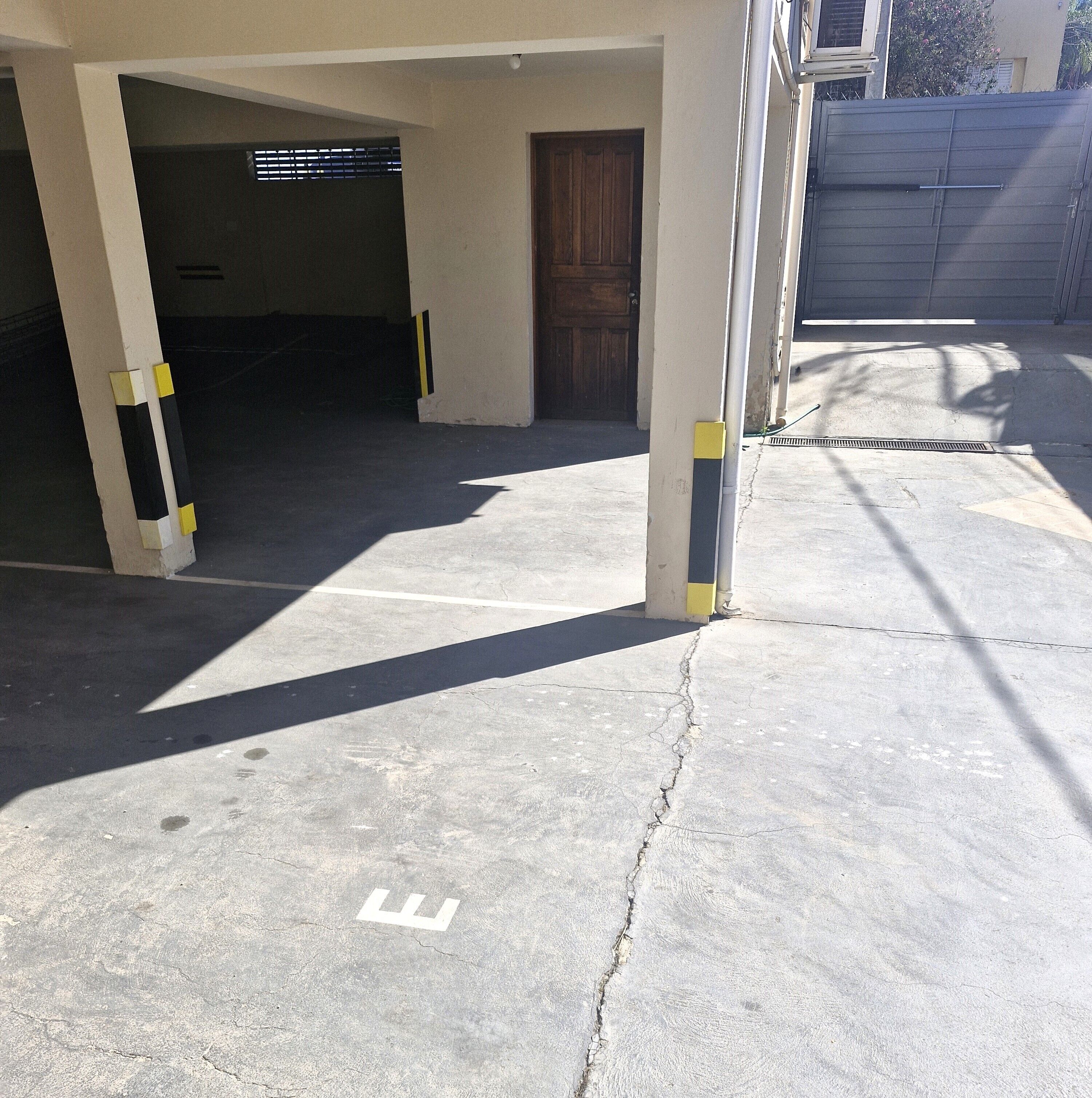A parking garage with concrete floors and columns, a door, and a chain-link fence.