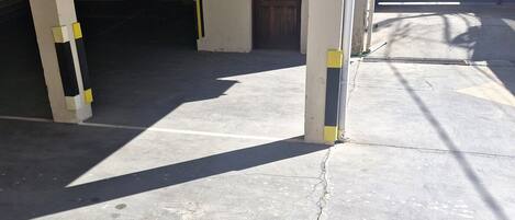 A parking garage with concrete floors and columns, a door, and a chain-link fence.
