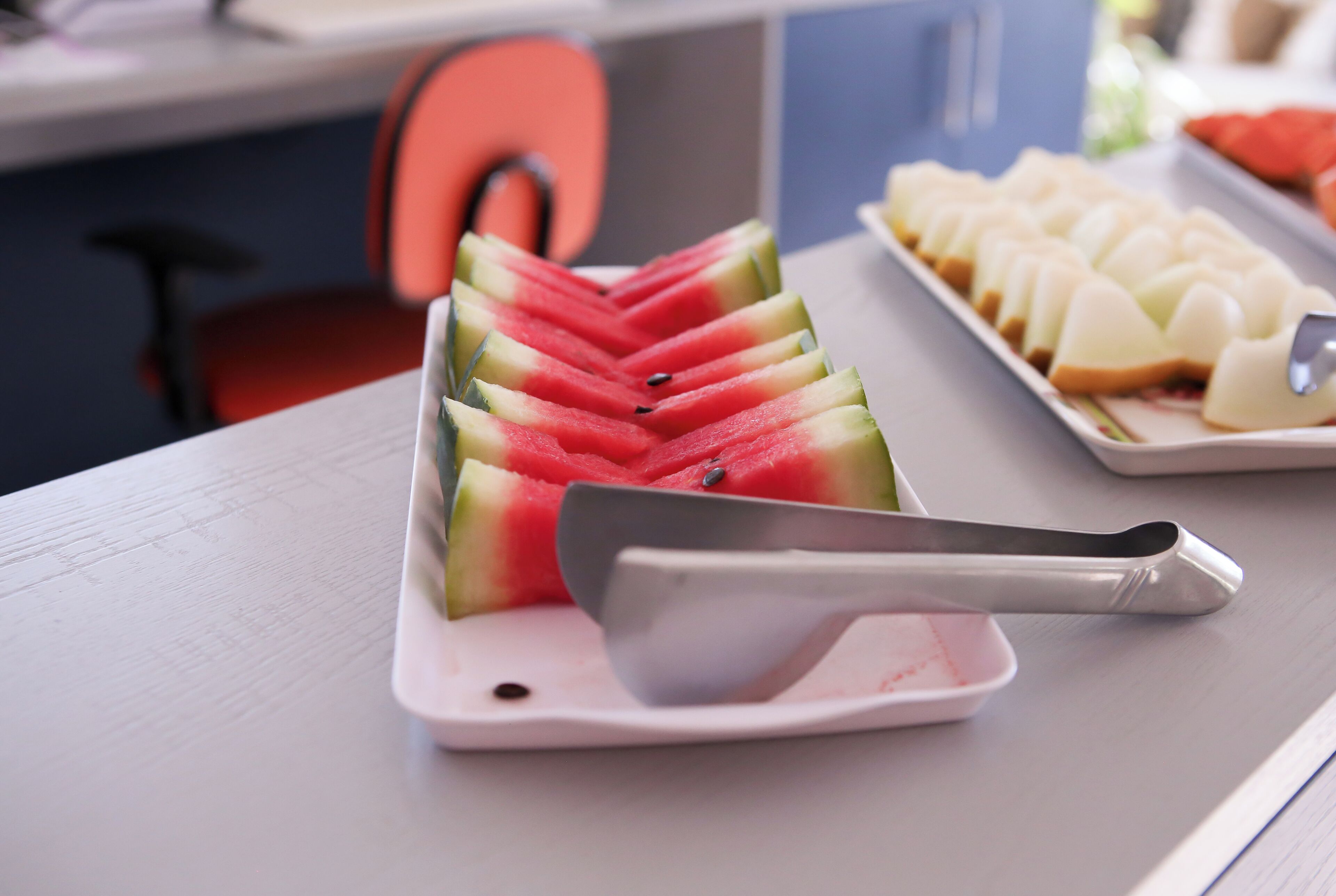 A white cutting board with watermelon slices and a knife on a table.