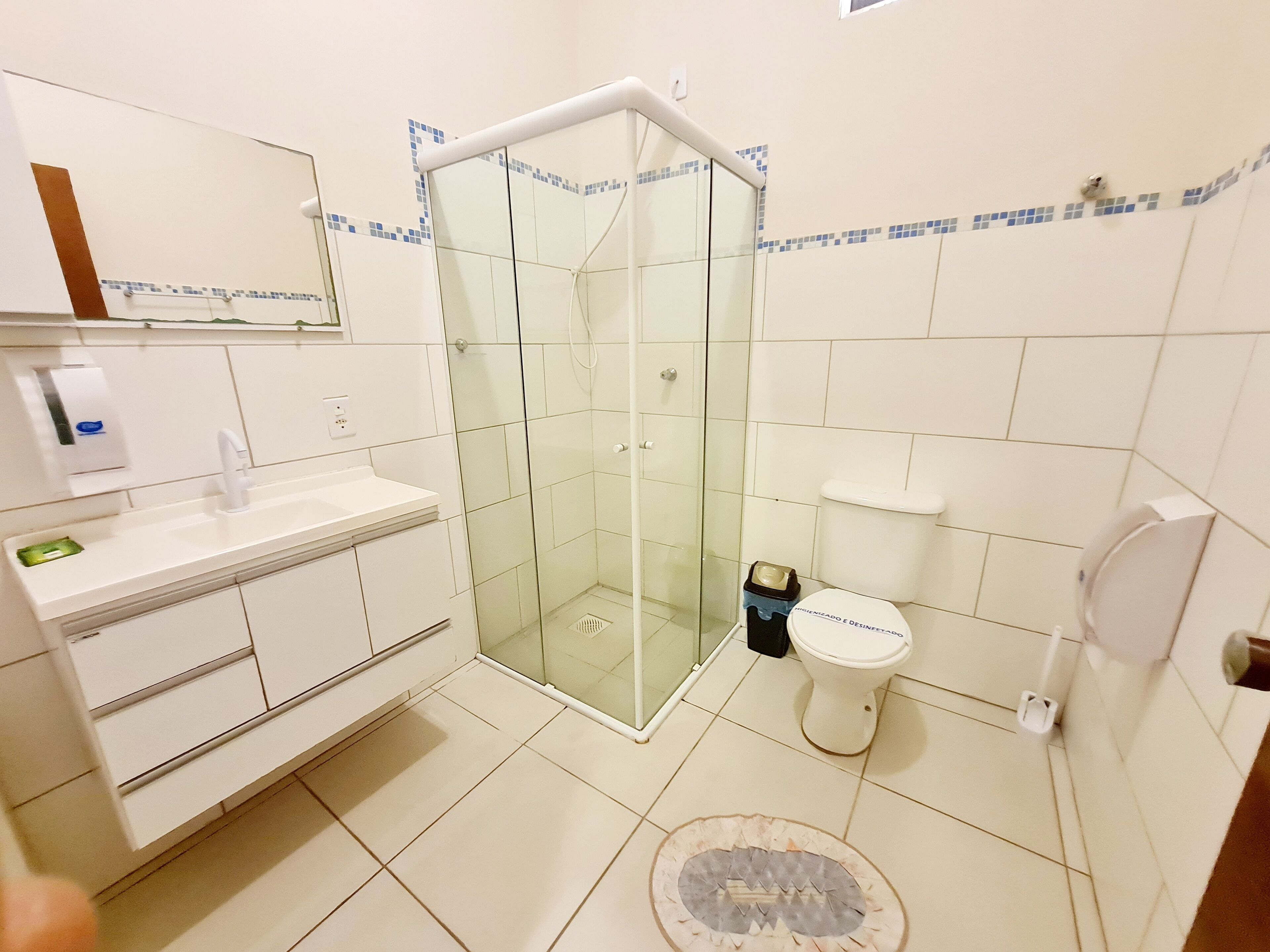 A bathroom with a glass-enclosed shower, a white sink, a toilet, and a mirror above the sink.