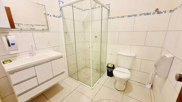 A bathroom with a glass-enclosed shower, a white sink, a toilet, and a mirror above the sink.