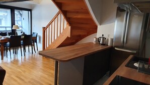 Una cocina moderna con una isla de madera, estufa integrada y un refrigerador de acero inoxidable.