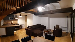 Un espacio habitable amplio con una escalera de madera, una cocina con electrodomésticos modernos y una zona de estar acogedora.