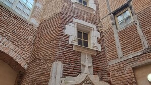 Un edificio histórico con una entrada central, varias ventanas y fachada de ladrillo.