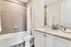 Ein Badezimmer mit einer Badewanne, Toilette und einem großen Spiegel über dem Waschbecken.