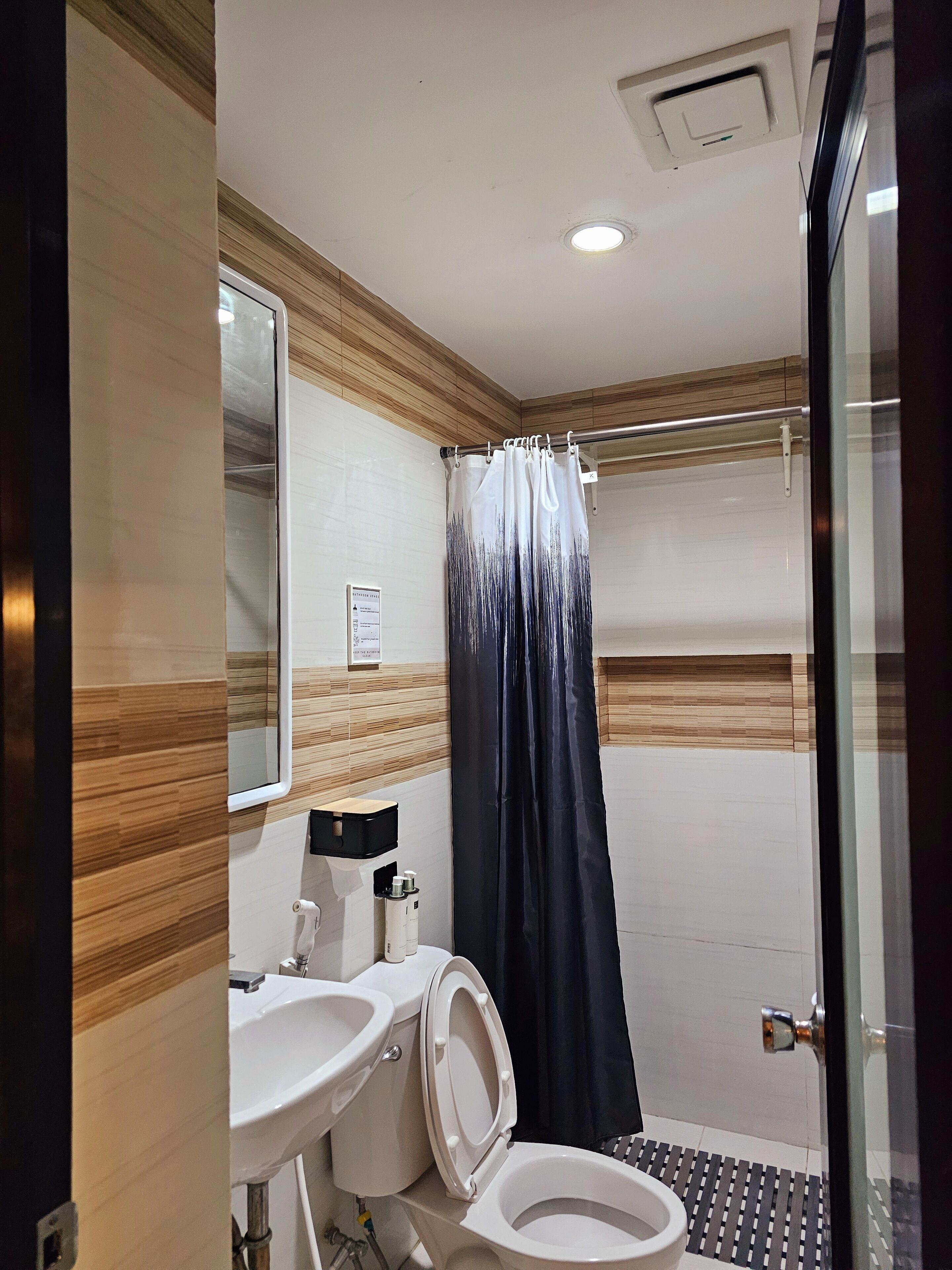 Un baño con inodoro, lavamanos y cortina de ducha.