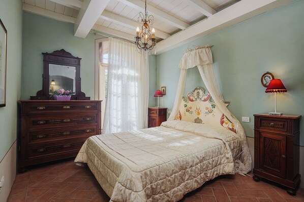 Un dormitorio con una cama con dosel, un aparador de madera, un espejo y una araña.